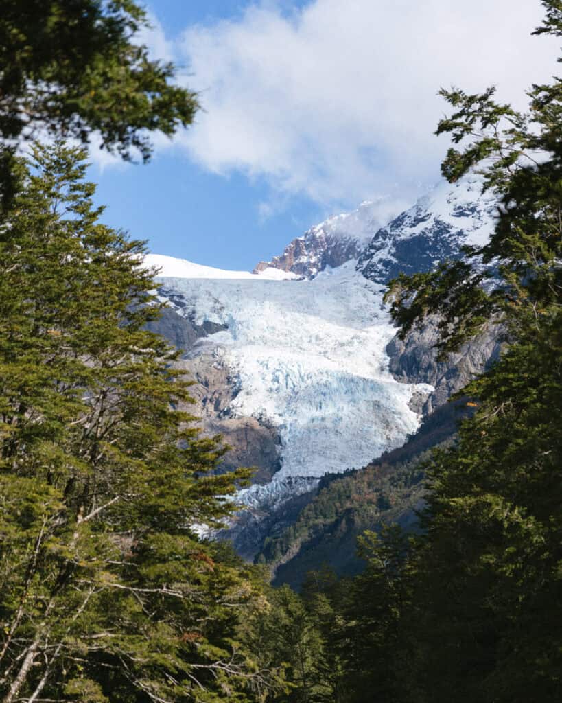Chaiten, Chile Travel Guide: A Town That Nearly Disappeared 1 Glacier in Chaitén seen under a bright blue sky, surrounded by tall snow-capped mountains and dense forest in the foreground.