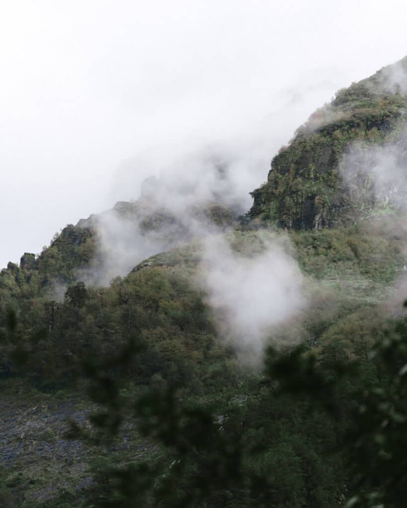Ventisquero Yelcho Hike Guide: Corcovado National Park, Chile 18 Cloud-covered hills blanketed in dense green forest near Chaitén, with low mist drifting across the ridges.