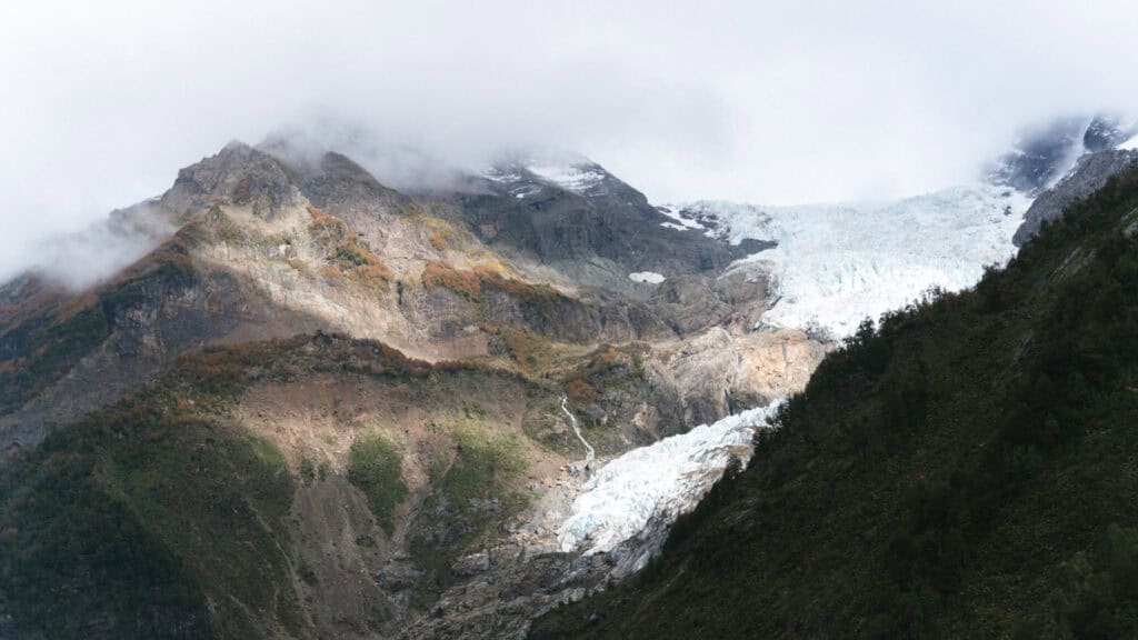 Chaiten, Chile Travel Guide: A Town That Nearly Disappeared 4 Broad landscape shot of Chaitén’s glacier with surrounding peaks colored in early autumn hues and patches of sunlight highlighting rocky textures.
