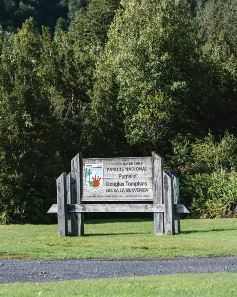 Chaiten, Chile Travel Guide: A Town That Nearly Disappeared 11 Wooden sign welcoming visitors to Parque Nacional Pumalín Douglas Tompkins, set on a lawn with forested background.