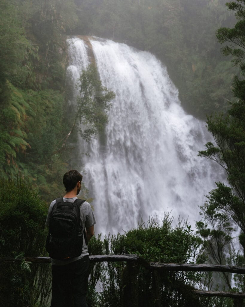 Chaiten, Chile Travel Guide: A Town That Nearly Disappeared 18 Brayden stands at a wooden overlook, facing a wide rainforest waterfall surrounded by mist.
