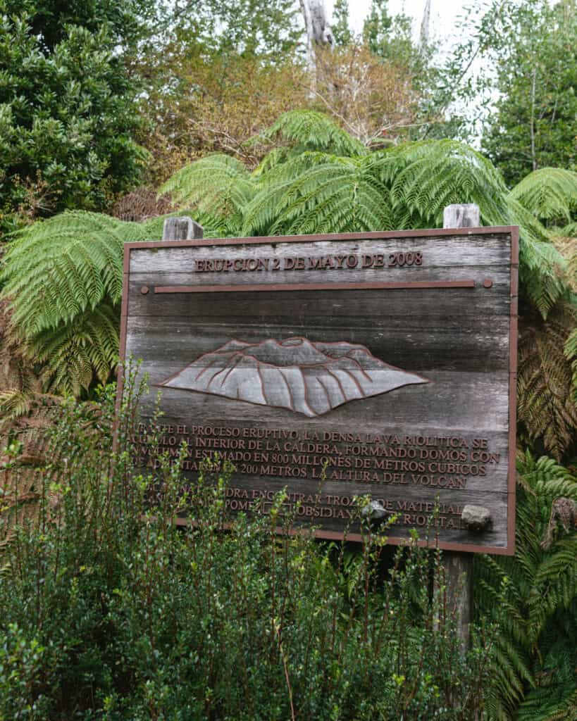 How to Visit the Pumalin National Park in Patagonia, Chile 28 Wooden sign showing an engraved volcano and text describing the Chaitén eruption on May 2, 2008, with technical details in Spanish.