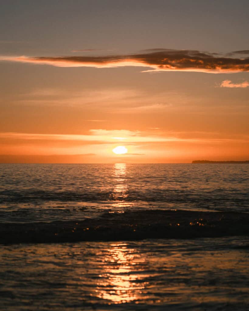 12 Best Things to Do in Drake Bay, Costa Rica 35 Fiery orange sun sets over the Pacific horizon, casting golden reflections across calm ocean waves under a glowing sky.