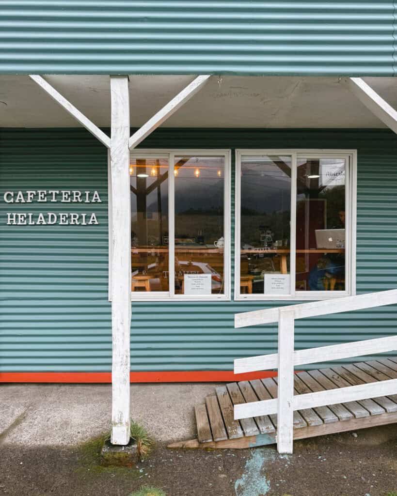 Chaiten, Chile Travel Guide: A Town That Nearly Disappeared 30 Exterior of a small teal-colored café and ice cream shop in Chaitén, with a wooden ramp leading to the door and warm lighting inside.