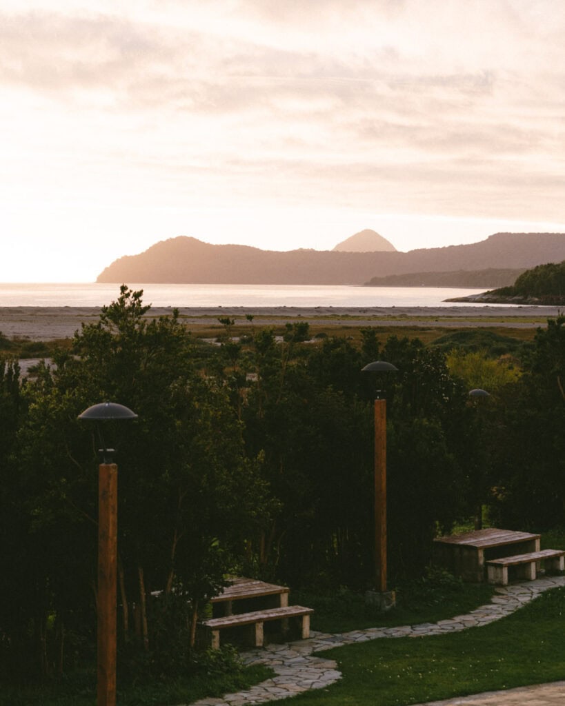 Chaiten, Chile Travel Guide: A Town That Nearly Disappeared 22 Early morning light over the bay near Chaitén, with distant hills and a small conical peak on the horizon viewed from a quiet park path.