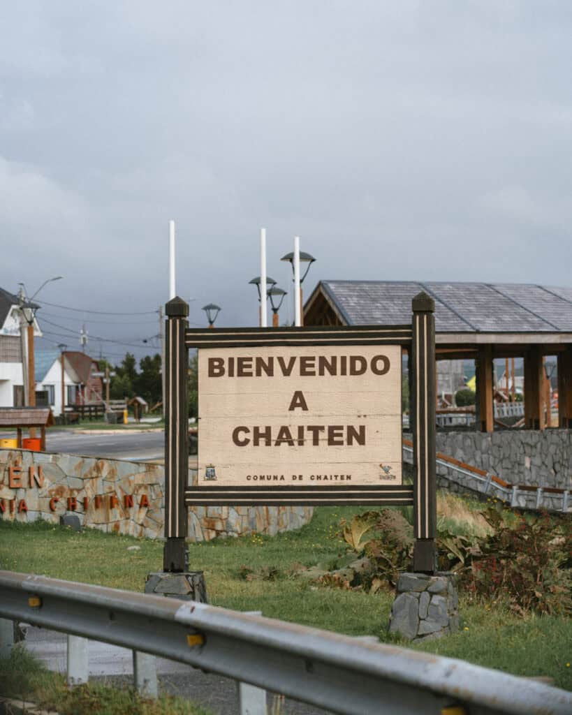 Chaiten, Chile Travel Guide: A Town That Nearly Disappeared 5 Large wooden sign reading “Bienvenido a Chaitén” stands at the town’s entrance, framed by stonework, lamp posts, and rooftops.