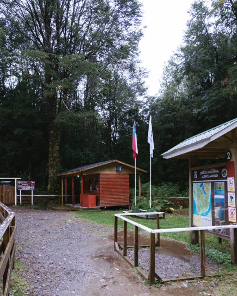 How to Visit the Alerce Andino National Park, Chile 12 Entrance area of Parque Nacional Alerce Andino, Chile, showing a wooden visitor hut, information boards, and flags of Chile and CONAF.