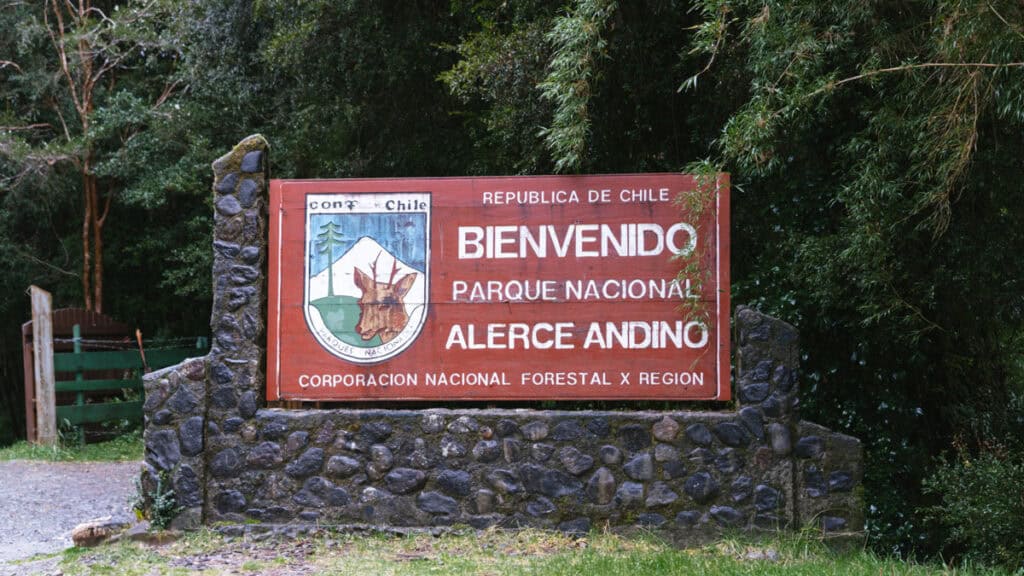 How to Visit the Alerce Andino National Park, Chile 5 Large wooden welcome sign reading “Bienvenido Parque Nacional Alerce Andino” with the CONAF emblem, mounted on a stone base.