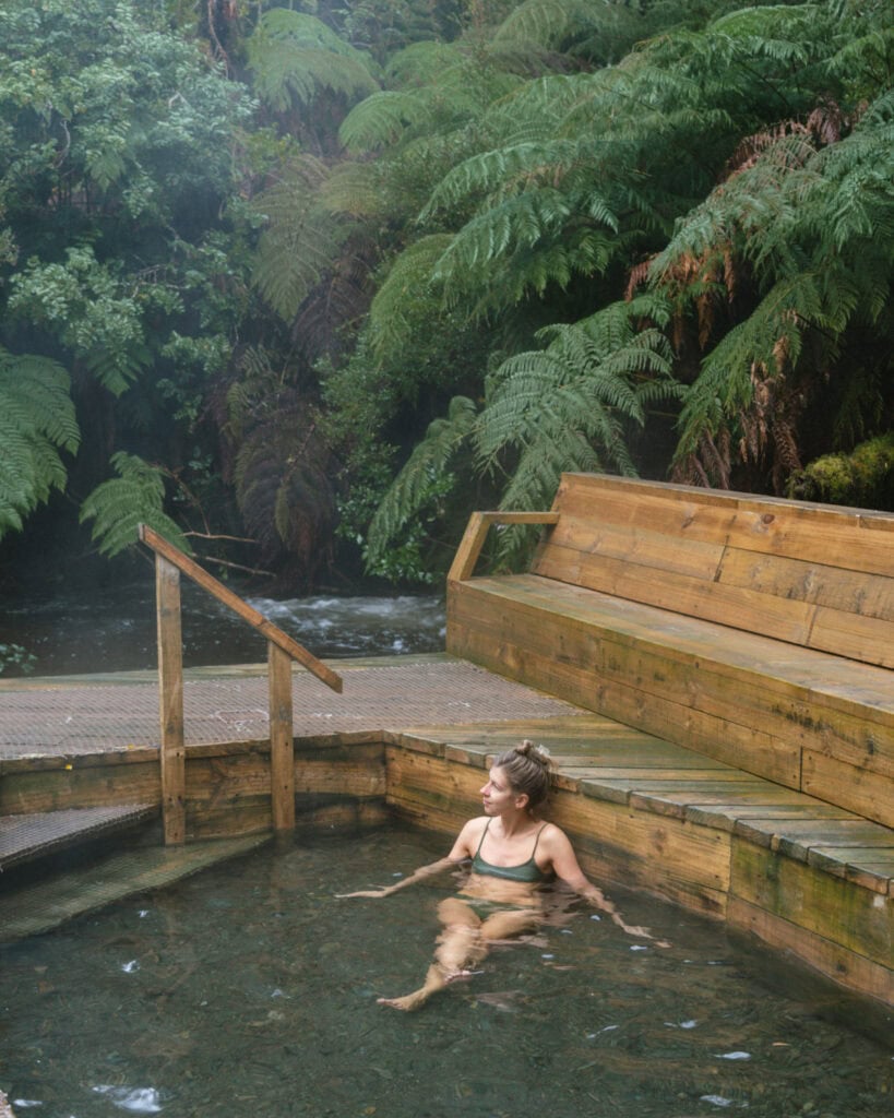 Chaiten, Chile Travel Guide: A Town That Nearly Disappeared 24 Sally sitting in a steaming hot spring pool surrounded by lush ferns and wooden seating in Hornopirén, Chile.