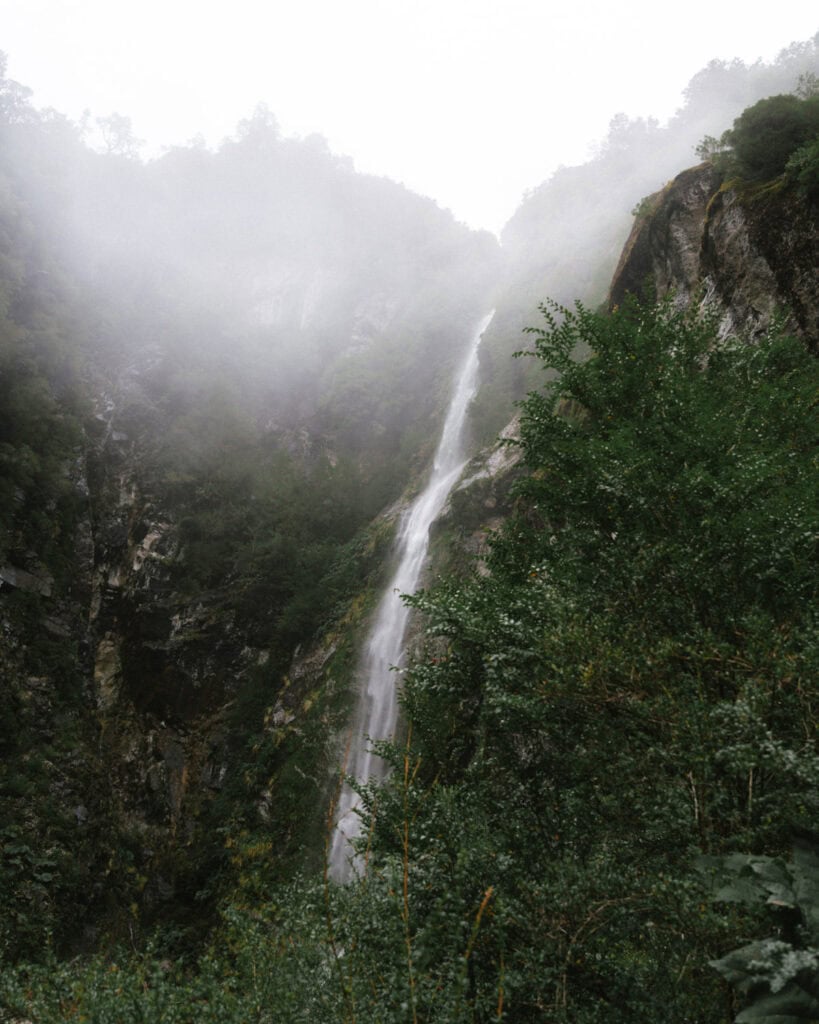 Puyuhuapi, Chile Travel Guide: Fjords and Hanging Glaciers 8 Tall waterfall cascading down a steep cliff surrounded by mist and dense vegetation in Parque Nacional Queulat, Chile.