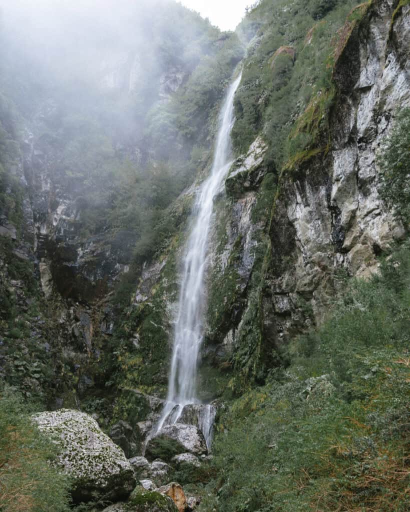 Puyuhuapi, Chile Travel Guide: Fjords and Hanging Glaciers 1 Wide view of Queulat waterfall plunging into rocks at the base of a lush canyon in Parque Nacional Queulat, Chile.