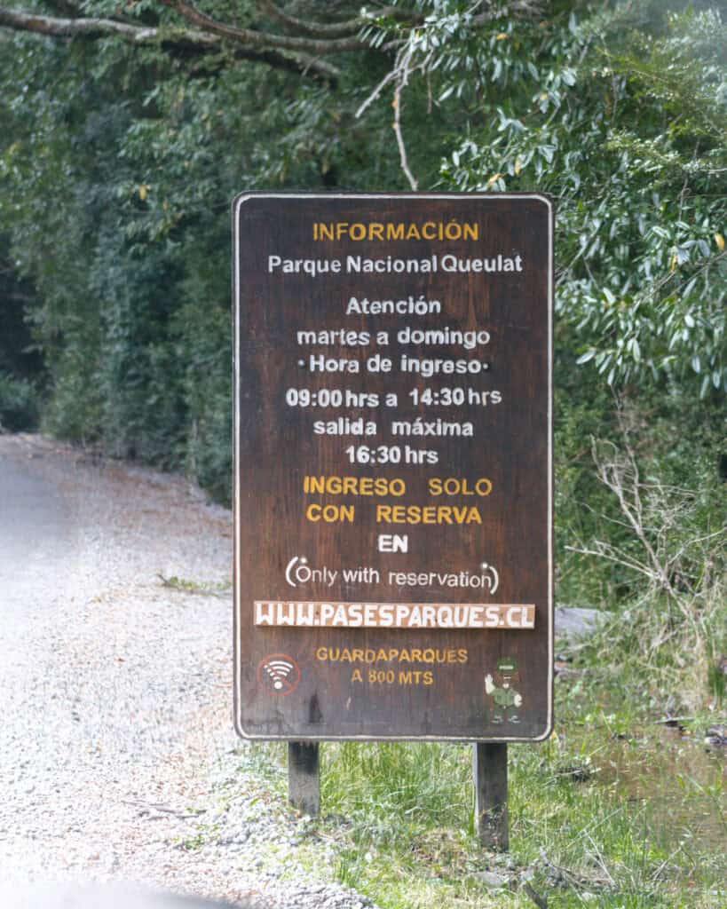 Queulat National Park: How to Visit the Ventisquero Colgante 6 Wooden sign with visitor information for Parque Nacional Queulat, including entry hours and reservation requirements, located near the entrance.