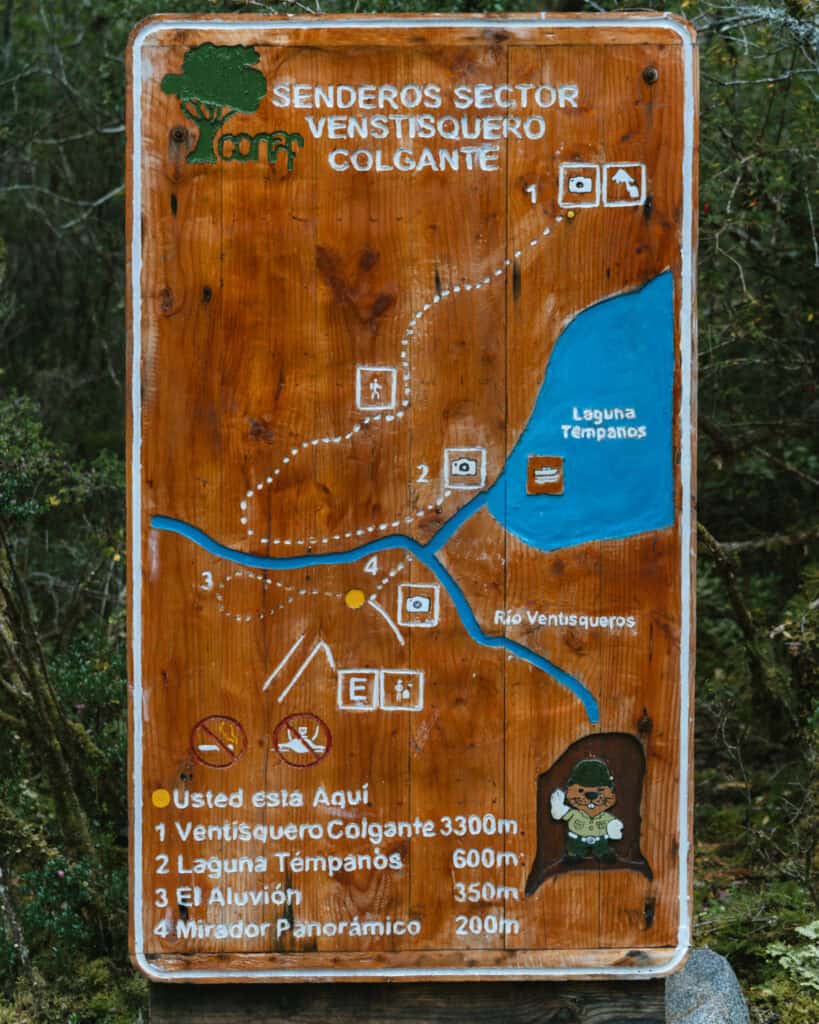 Puyuhuapi, Chile Travel Guide: Fjords and Hanging Glaciers 11 Wooden trail map showing hiking routes to Ventisquero Colgante, Laguna Témpanos, El Aluvión, and Mirador Panorámico in Parque Nacional Queulat, Chile.