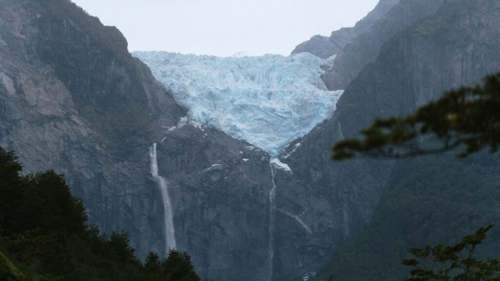 Puyuhuapi, Chile Travel Guide: Fjords and Hanging Glaciers 16 Wide horizontal view of the Hanging Glacier with two waterfalls streaming down into the valley in Parque Nacional Queulat, Chile.