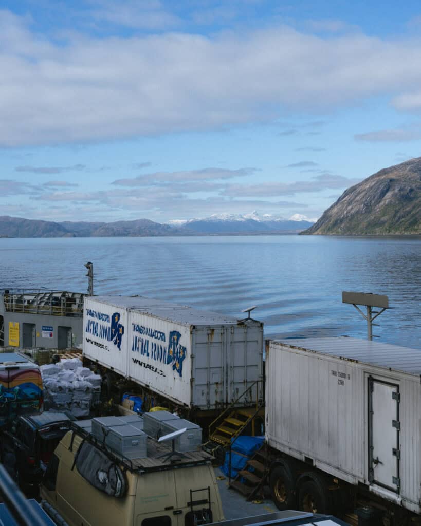 TABSA Ferry: Sailing from Puerto Natales to Puerto Yungay 9 View from the upper deck of the Tabsa Ferry in Chile showing large white cargo containers labeled “Transbordadora Austral Broom” and a panoramic backdrop of snow-capped mountains across the fjord.