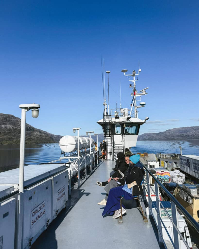 TABSA Ferry: Sailing from Puerto Natales to Puerto Yungay 35 Passengers wrapped in winter gear sit on benches atop the ferry, enjoying the sun and mountain views as the vessel glides through southern Chilean fjords.
