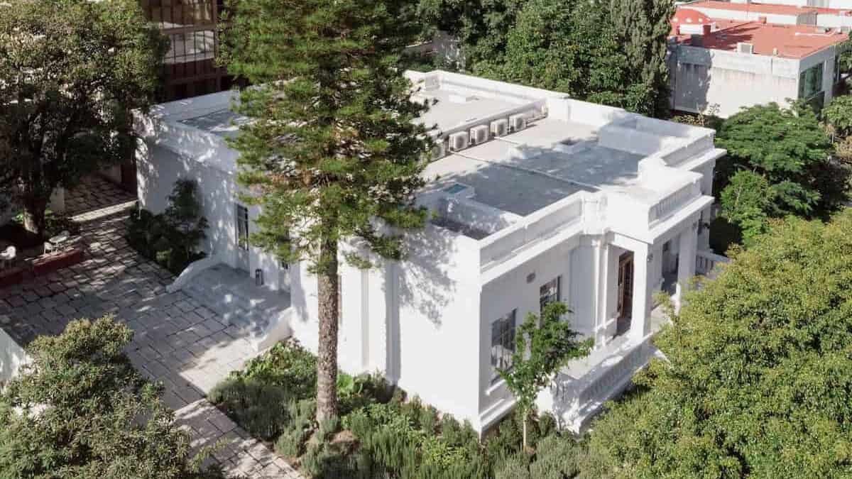 Complete 5-Day Guadalajara Itinerary for First Timers 37 Aerial view of Casa Bosque Eduviges, a white neoclassical building in Guadalajara, Mexico, surrounded by tall trees and lush greenery. Located in the Colonia Americana neighborhood, the building features columned entrances, a flat rooftop with air conditioning units, and a stone pathway leading through a landscaped garden.
