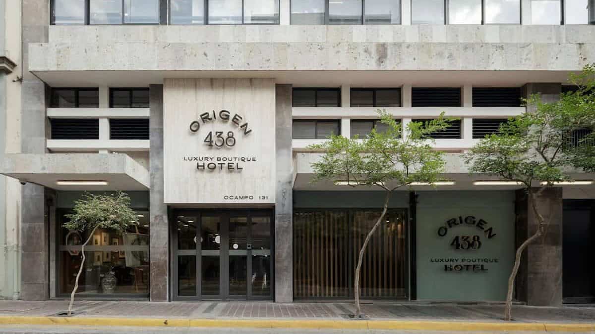 Complete 5-Day Guadalajara Itinerary for First Timers 36 Street-level view of Origen 438 Luxury Boutique Hotel in Guadalajara, Mexico, featuring a modern facade with large windows, minimalist stone detailing, and two small trees flanking the entrance. Located on Ocampo Street in the Centro Histórico district, the building’s signage is prominently displayed in bold black letters above the main glass doors.