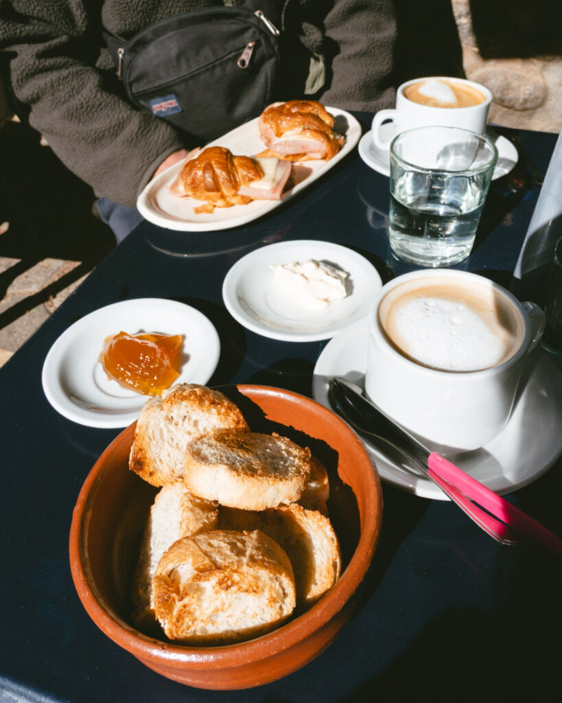 7 - 10 Day Salta Road Trip: The Best of Northwest Argentina 52 Traditional Argentine breakfast with coffee, toast, jam, cream cheese, and medialuna sandwiches, served outdoors on a navy-blue table.