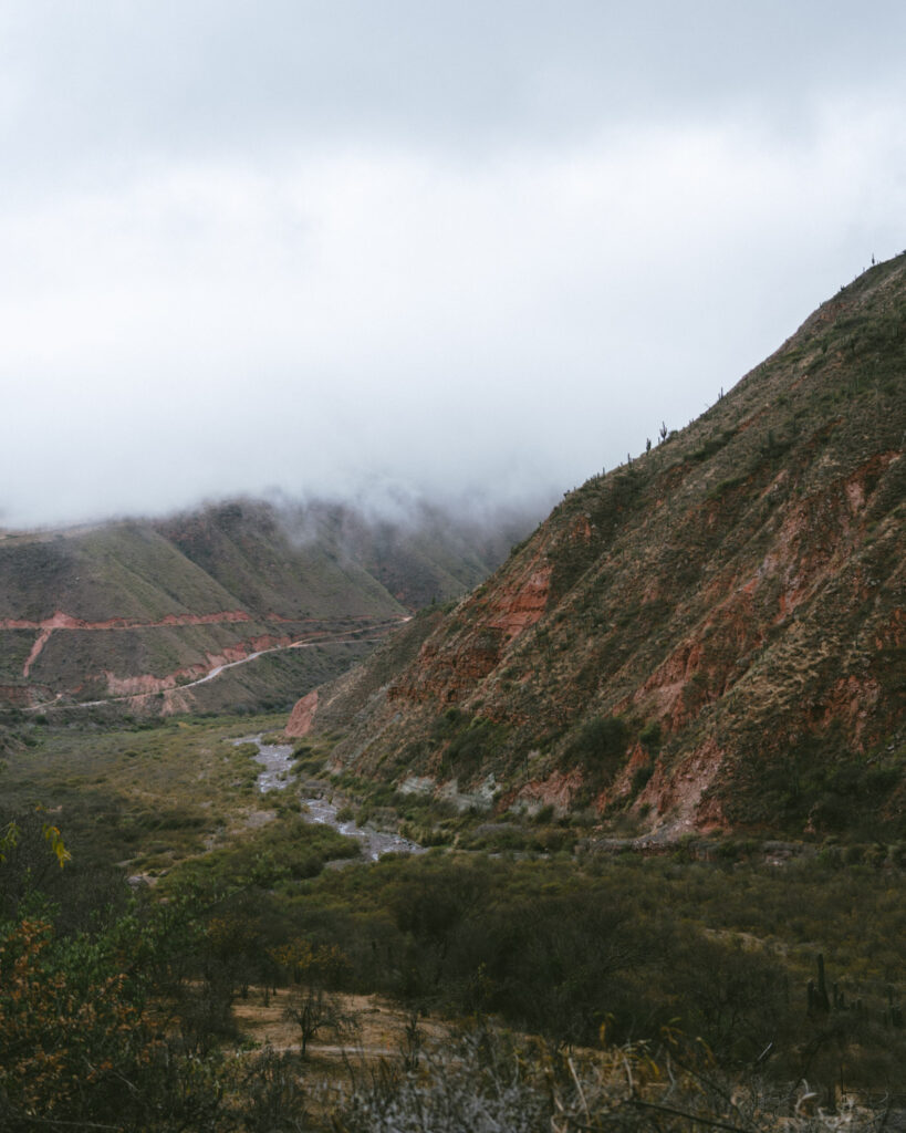 7 - 10 Day Salta Road Trip: The Best of Northwest Argentina 66 A narrow river winds through a deep green valley flanked by red hills and overcast skies in the Andes near Cachi.