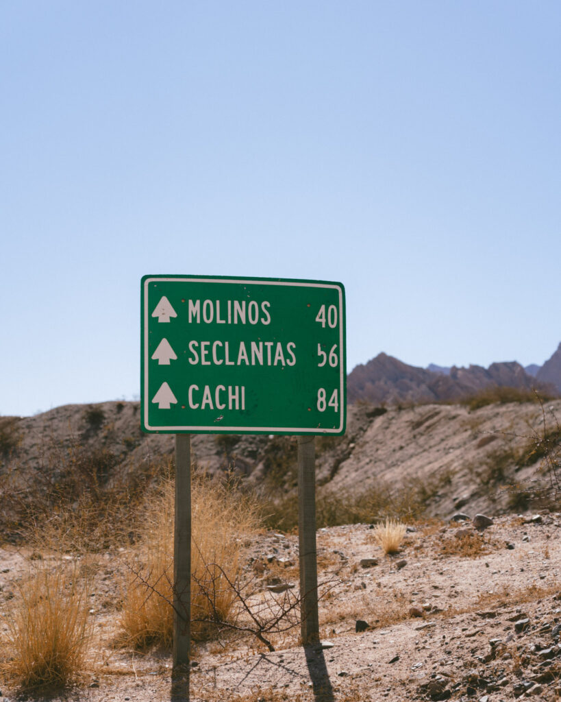 7 - 10 Day Salta Road Trip: The Best of Northwest Argentina 41 Green road sign shows distances to Molinos (40 km), Seclantás (56 km), and Cachi (84 km), set in a dry desert landscape.