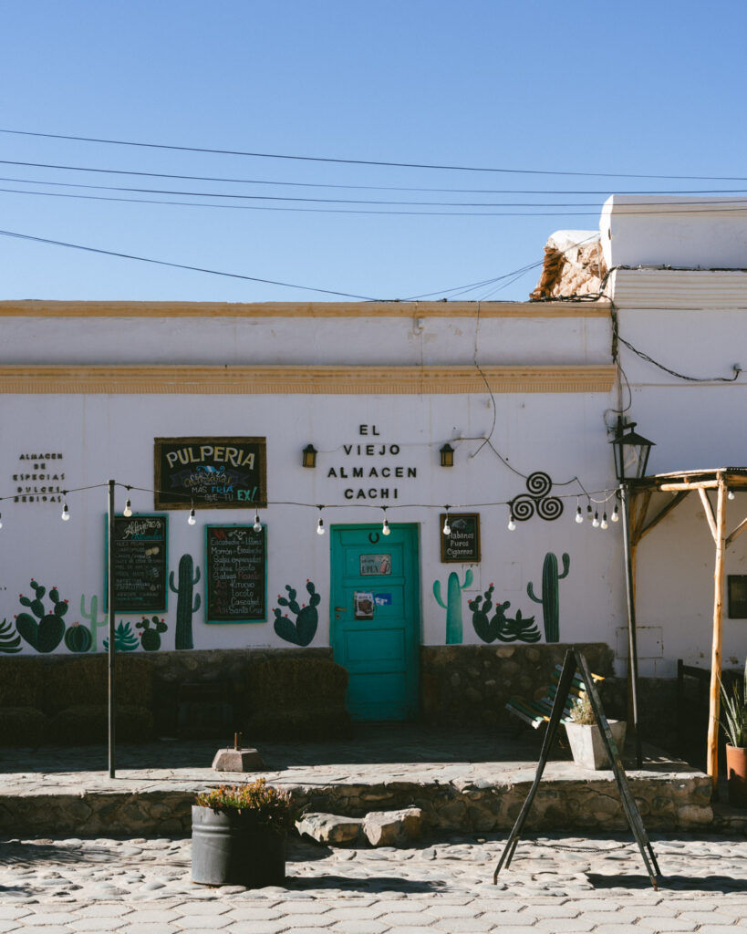 7 - 10 Day Salta Road Trip: The Best of Northwest Argentina 51 Vertical view of El Viejo Almacén Cachi's vibrant storefront with painted cacti, hanging lights, and rustic signage.