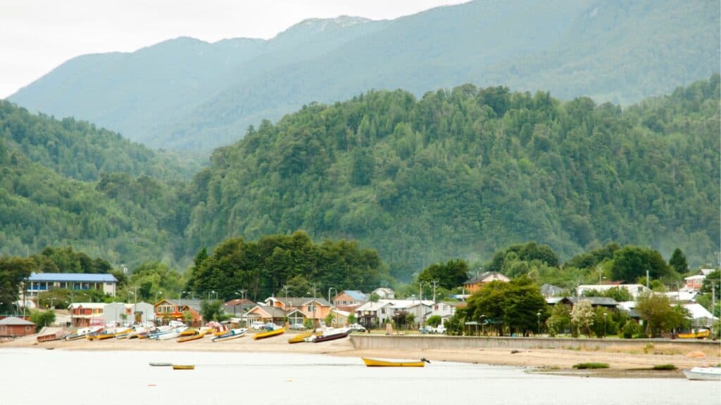 The Carretera Austral, Chile: Everything You Need to Know 34 The small seaside port town of Puerto Cisnes on the Carretera Austral in Chile, Patagonia. Moody grey skies meet forest clad hills rising up behind the tiny village on the waterfront.