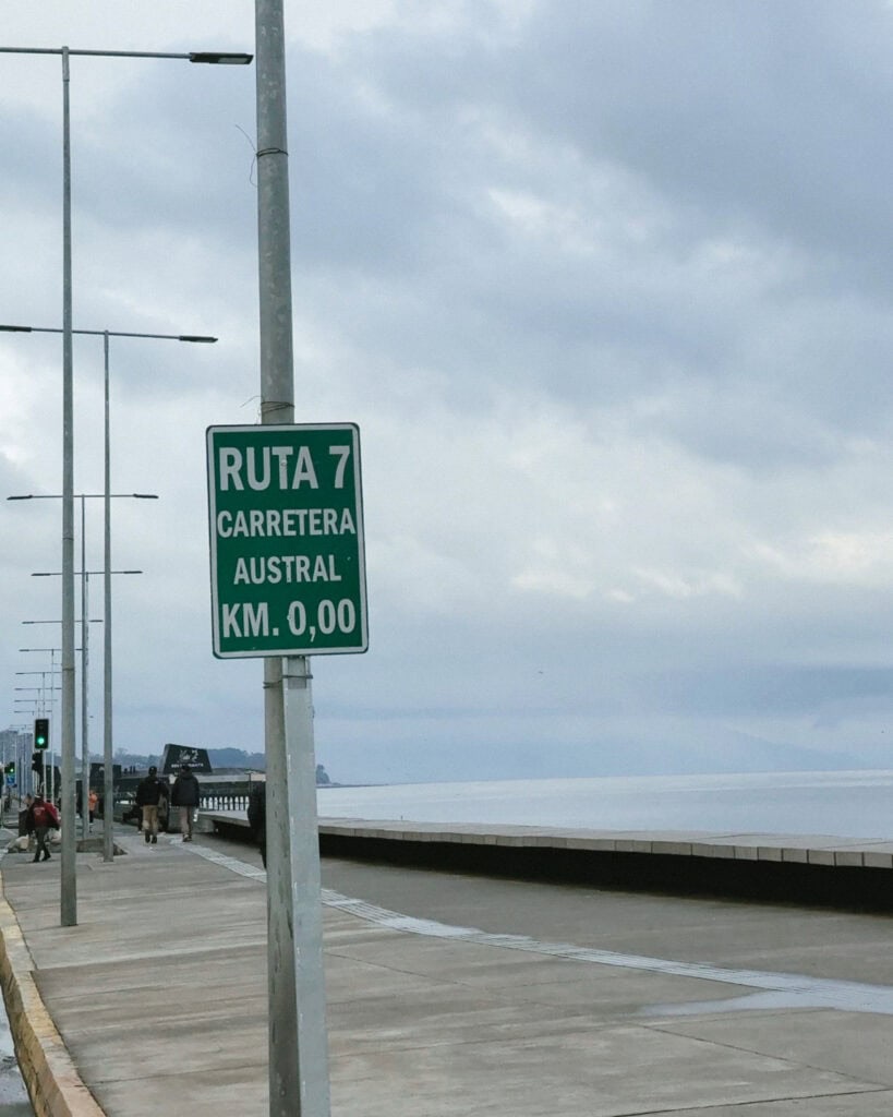 The Carretera Austral, Chile: Everything You Need to Know 19 A small green road sign on a pole on the waterfront in Puerto Montt in Chile, marking the beginning of the Carretera Austral. Ruta 7 KM 0.00.