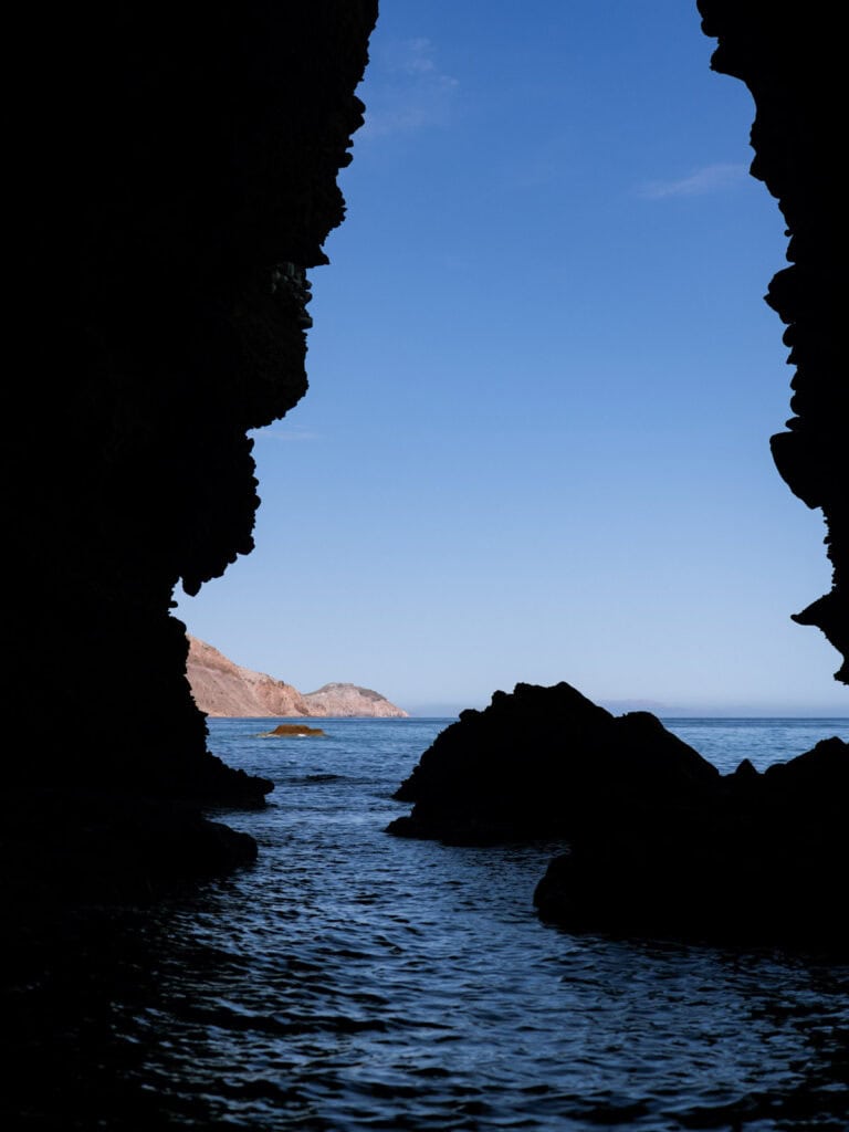 Our Day at Isla Espiritu Santo, La Paz: Sea Lions & Beaches 17 View from inside a dark sea cave looking out toward bright blue water and rocky cliffs along the coast of Isla Espiritu Santo in La Paz Baja California Sur.