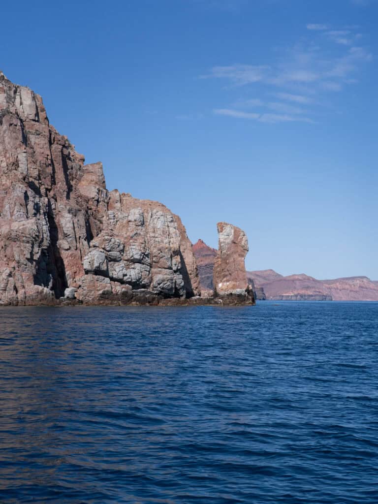 23 Best Things to Do in La Paz, Baja California Sur, Mexico 16 Tall rugged rock formations rise from the ocean along the dramatic coastline of Isla Espiritu Santo in La Paz Baja California Sur beneath a clear sky.