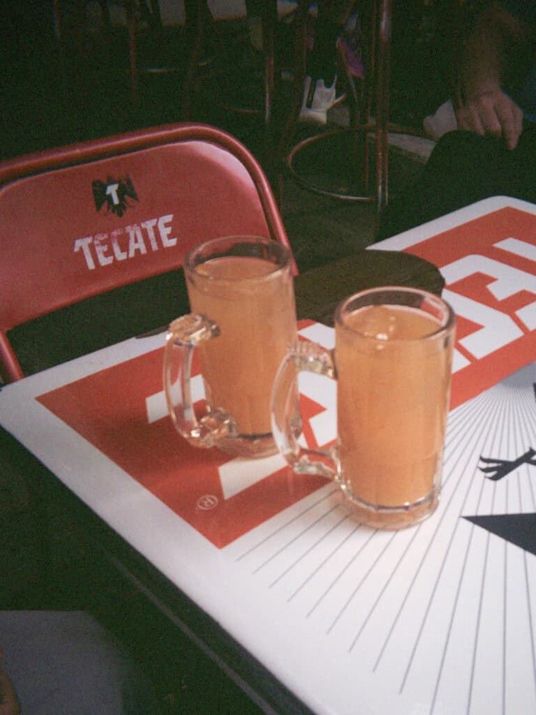 Mexico City Food Tour: Our Experience with Sherpa Food Tours 6 Two frosty beer mugs sit on a table with a bold red and white "TECATE" logo during a Mexico City food tour stop at a casual bar setting.