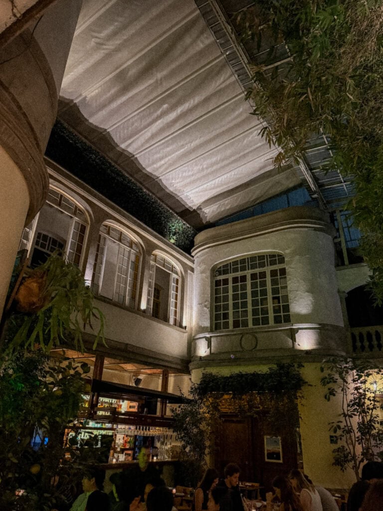 Mexico City Food Tour: Our Experience with Sherpa Food Tours 17 A warmly lit courtyard restaurant in Mexico City features tall bamboo plants, arched windows, and diners seated at tables enjoying a food tour experience.