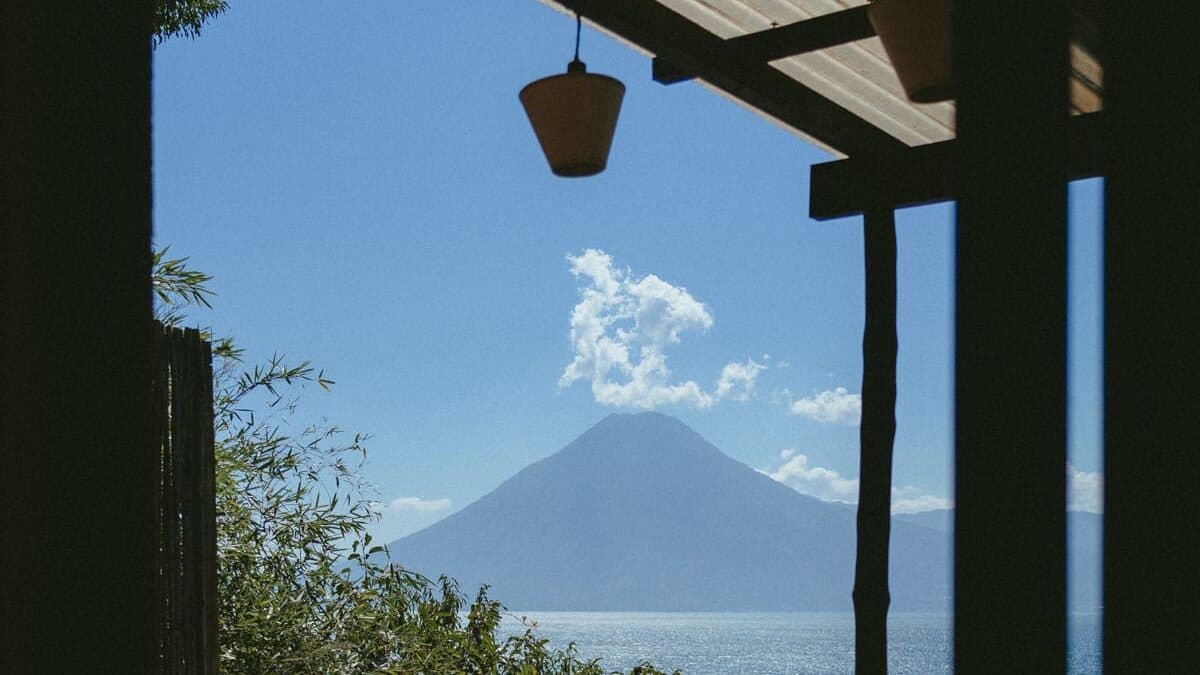 Lake Atitlan Itinerary: How to Spend 7, 5 or 3 Nights 7 A picturesque view of a volcano and Lake Atitlan from a patio, with a bottle of wine and a glass in the foreground. The scene captures the tranquility of the setting, perfect for relaxing and enjoying the view.
