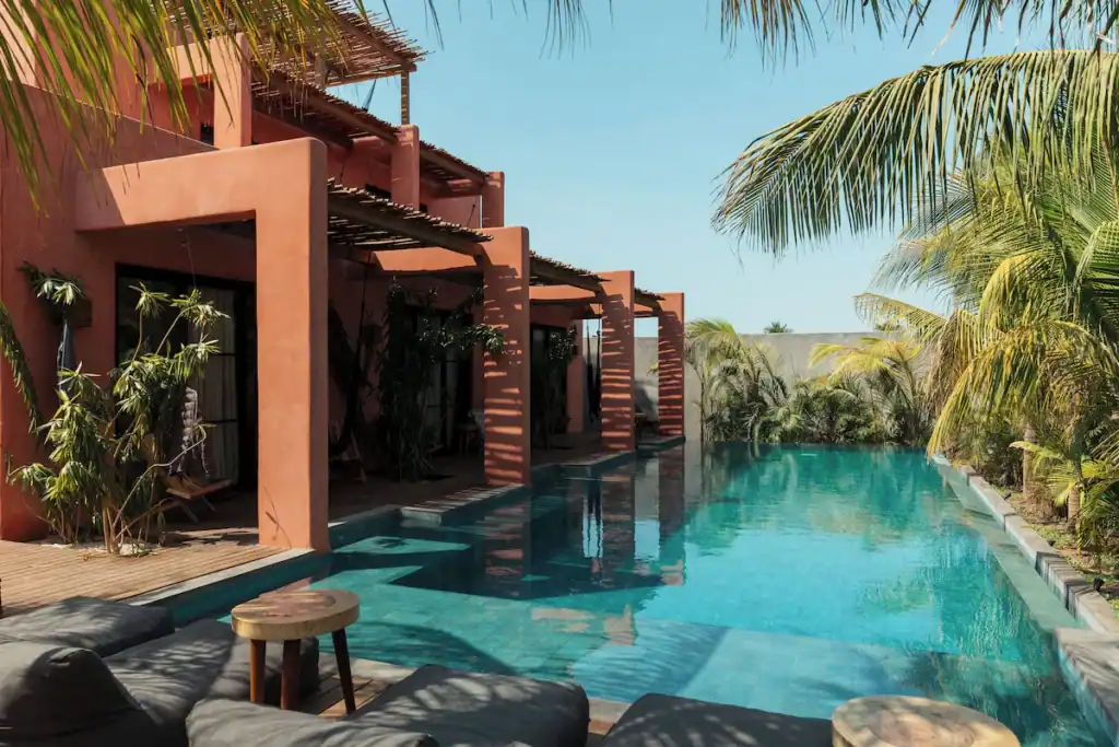 Everything You Need to Know About El Paredon Guatemala 9 Tropical pool lined with palm trees and modern terracotta villas at Swell Lifestyle Surf Hotel in El Paredón, Guatemala.
