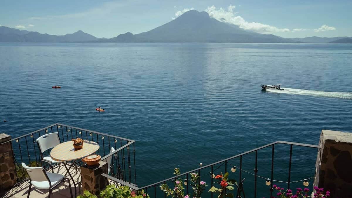Lake Atitlan Itinerary: How to Spend 7, 5 or 3 Nights 8 Lakefront terrace with flowers, outdoor seating and panoramic volcano views at La Casa del Mundo in Jaibalito, Lake Atitlán, Guatemala.